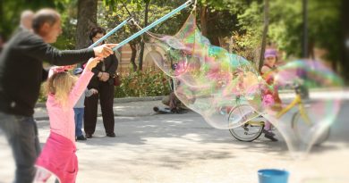 En El Retiro de Madrid: Niña haciendo pompas inmensas de jabón ayudado por un adulto